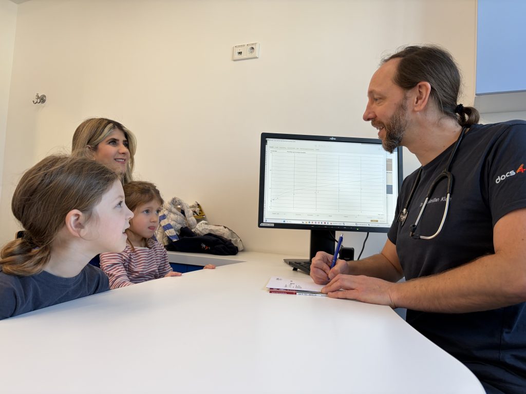Arzt im Gespräch mit Mutter und zwei Kindern