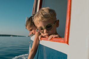 Kind mit grüner Brille schaut vom Boot