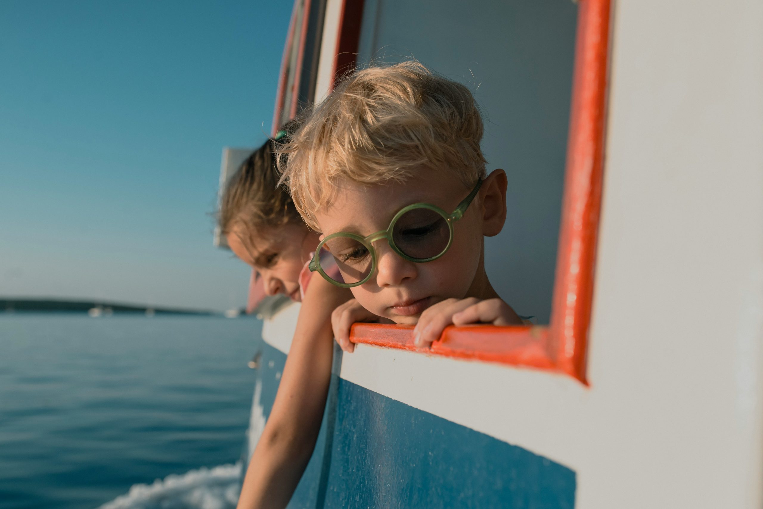 Kind mit grüner Brille schaut vom Boot